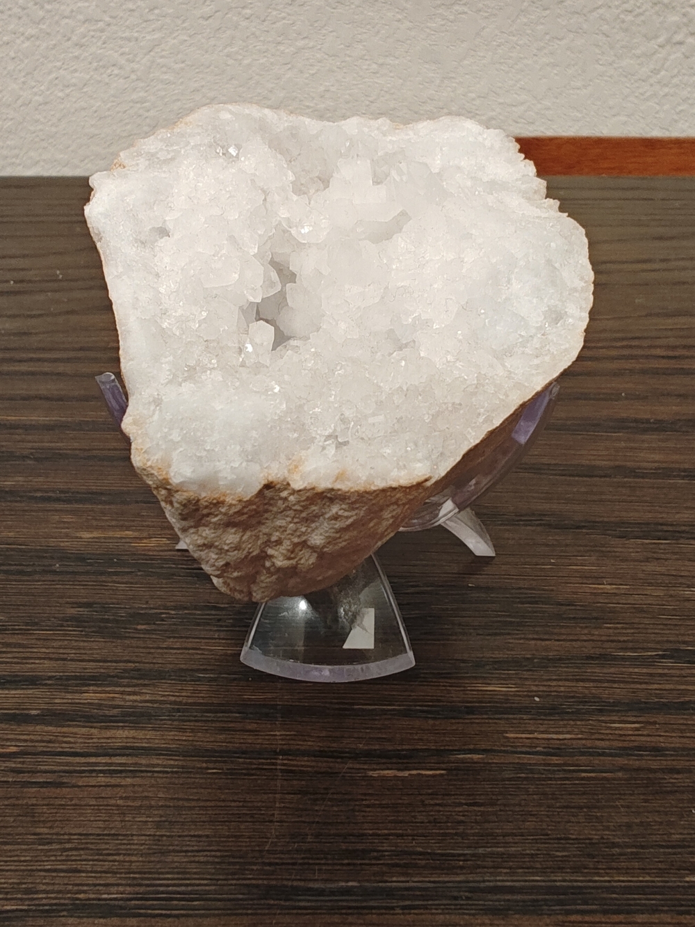 natural white quartz crystal geode cluster rests on a clear acrylic display